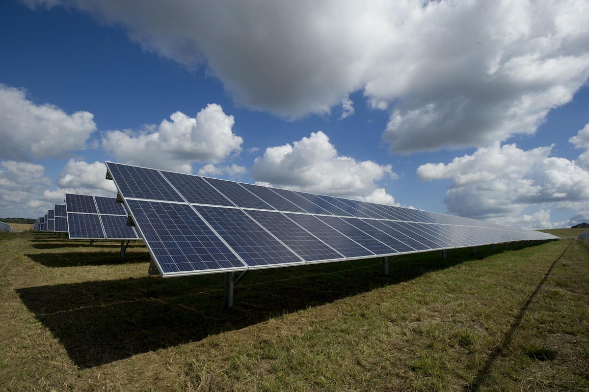 Rows of solar panels being cleaned under a bright sky